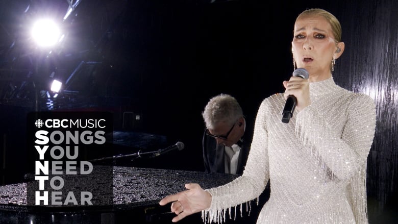 Cline Dion performs with a pianist in the background. She is wearing a white dress covered in crystals. The CBC Music logo and the  text 