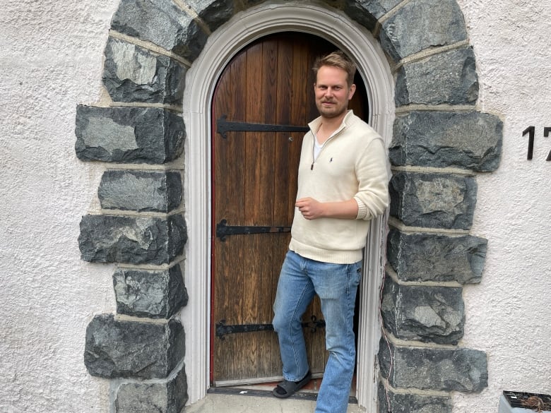 A man standing outside a wooden door.