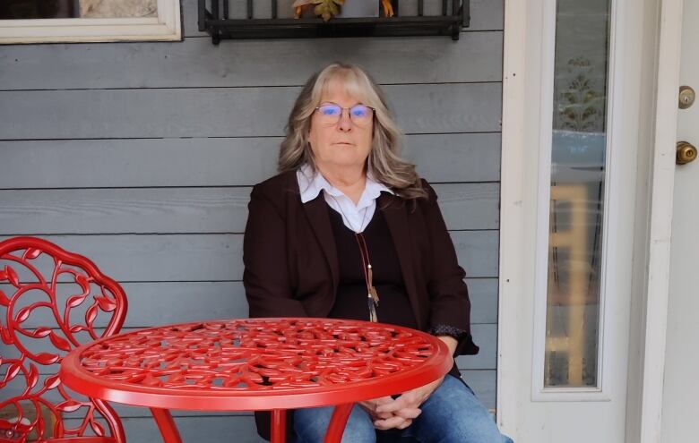 A woman sits at a patio table.