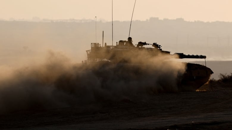 A soldier seen atop a moving tank.