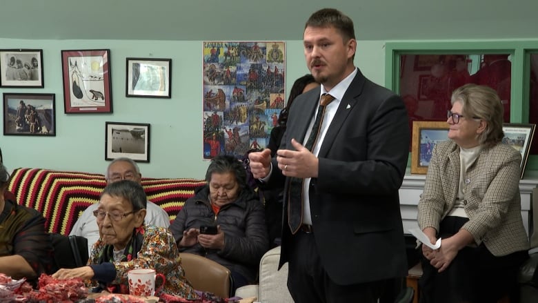 a man standing, surrounding by people