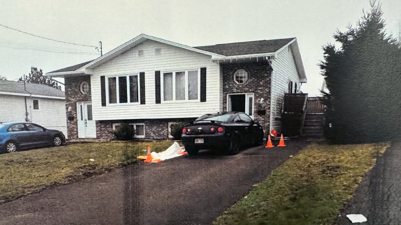 A car parked outside a duplex with tarps and cones around the vehicle.