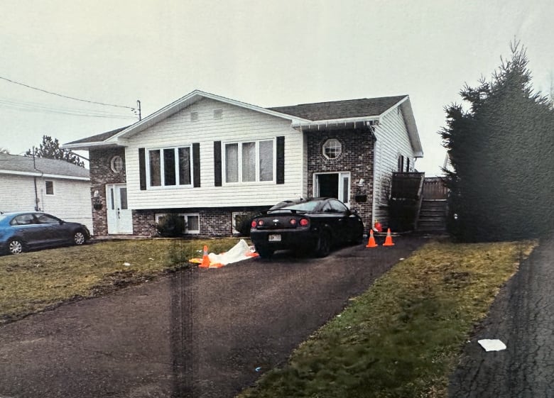 A car parked outside a duplex with tarps and cones around the vehicle.