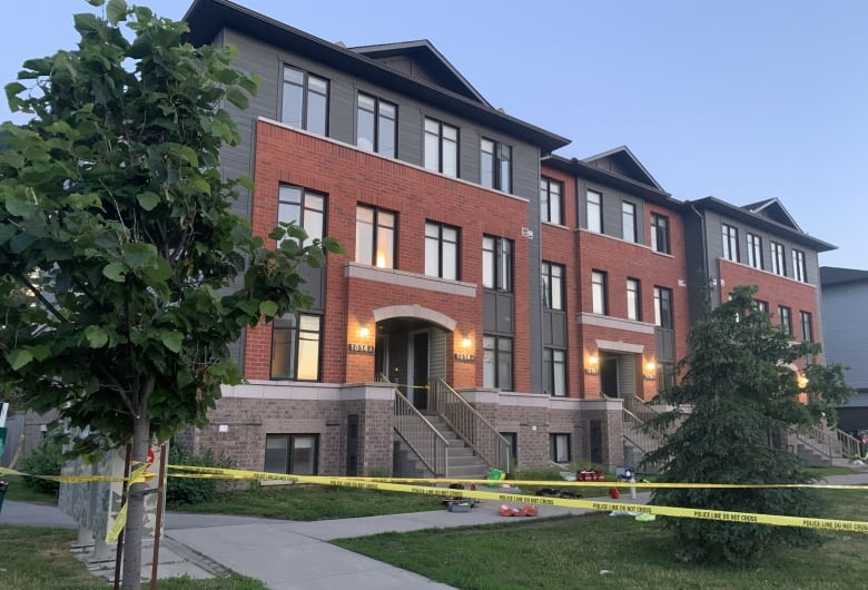 Police tape in front of a rowhouse complex.