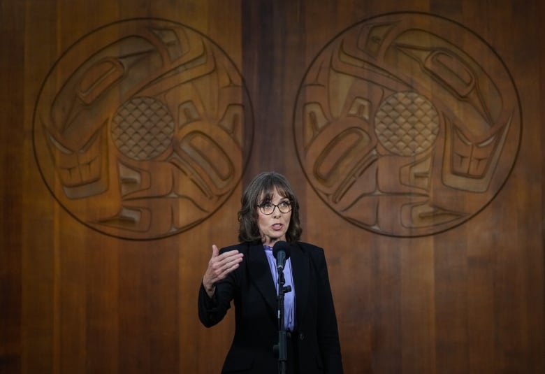 A woman in front of a large wooden wall.