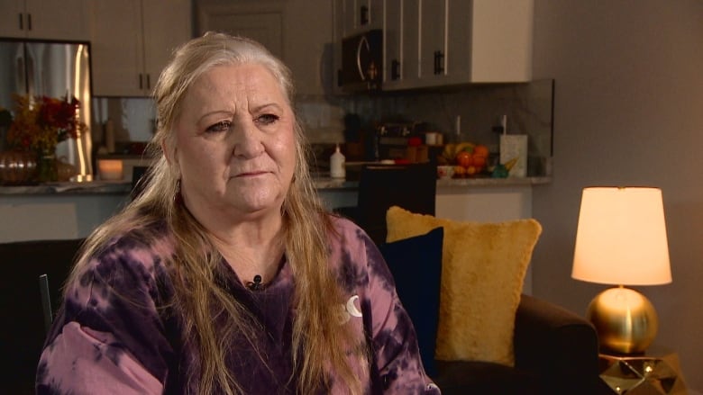 A woman sits on a couch inside a home.