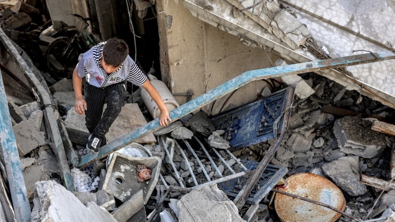 A boy climbs through rubble