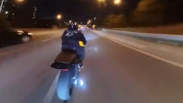 A man on a motorcycle drives at high speeds at night.