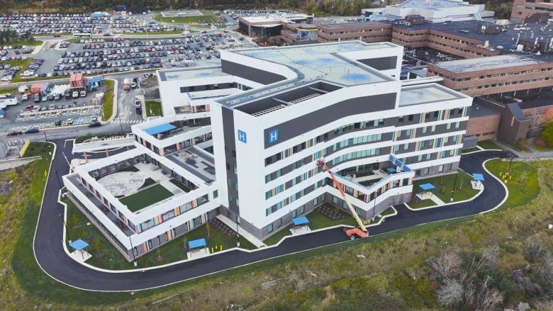 A drone photo of a large white building with colourful windows. It's attached to a large brown building.