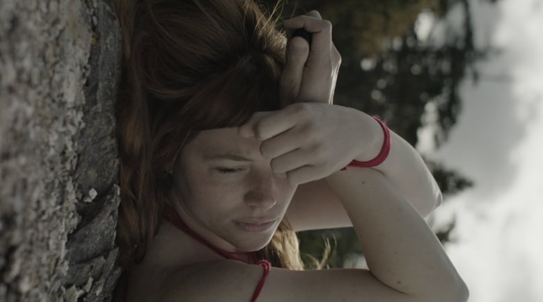 A women with her arms crossed over her head, laying on the ground.