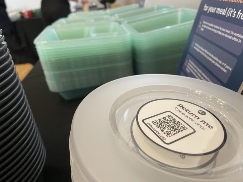 Transparent reusable take out containers with a QR code on the lid.