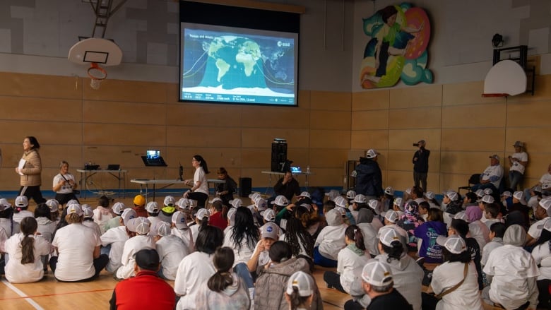 a group of children sitting in a school gymnasium