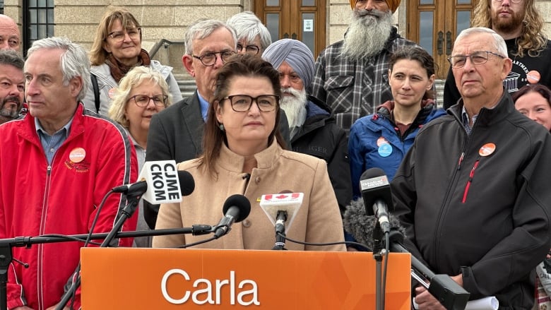 A woman spaeks at a podium labelled 