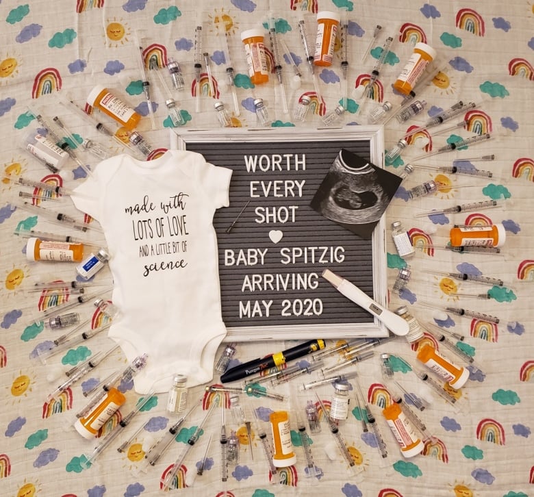 A baby announcement and jumper surrounded by pills and srynges 