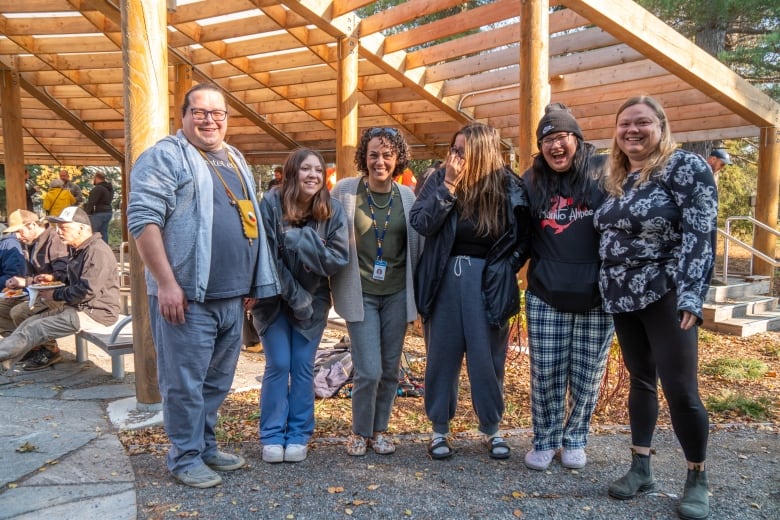 A group of people stand outside, smiling and laughing.