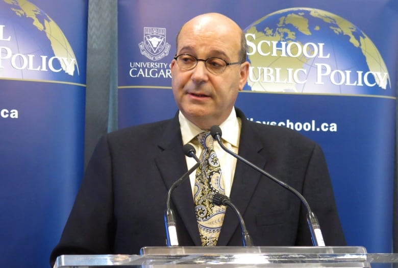 A man speaks to reporters at a podium.