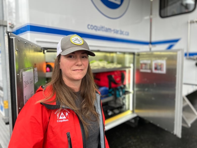 A woman smiles while in front of a truck containing emergency supplies.