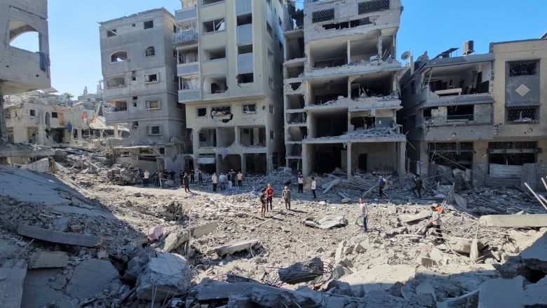 People gather gather at a site featuring heavily destroyed buildings following an airstrike.