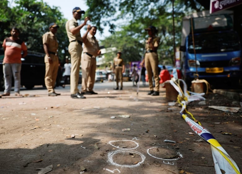 Police stand near an outdoor crime scene.