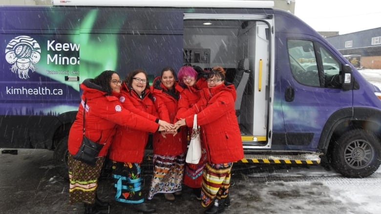 people pose in front of van