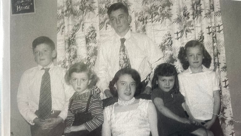 An old portrait of six siblings dressed up. 