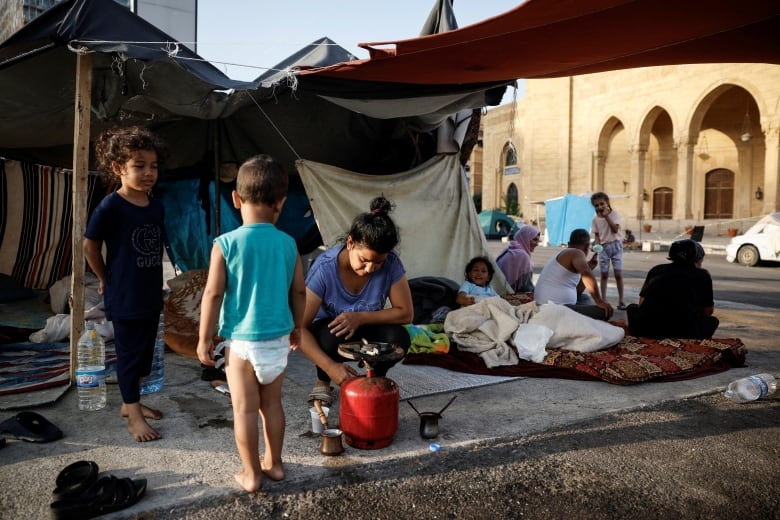 A displaced woman prepares coffee by a makeshift shelter, amid hostilities between Hezbollah and Israeli forces, in central Beirut, Lebanon, October 16, 2024. 