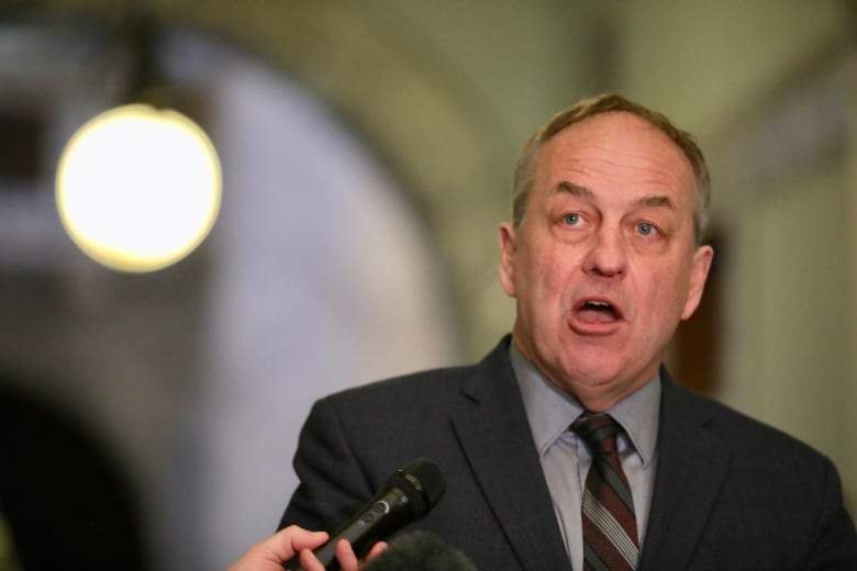 A man speaks in a legislature corridor.