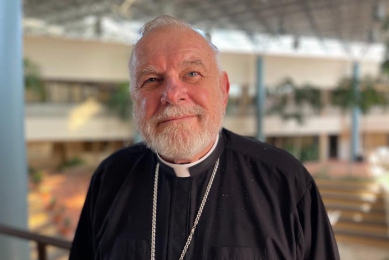 A Christian bishop is shown in a church wearing a clerical collar.