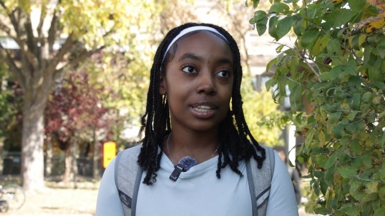 A young Black teenager speaks to a reporter outside her school