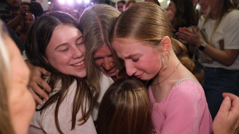 A woman hugging three young girls.