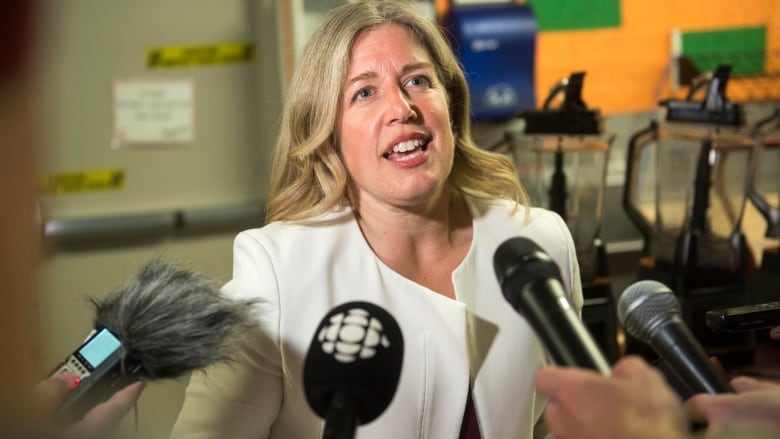 Woman speaking surrounded by microphones