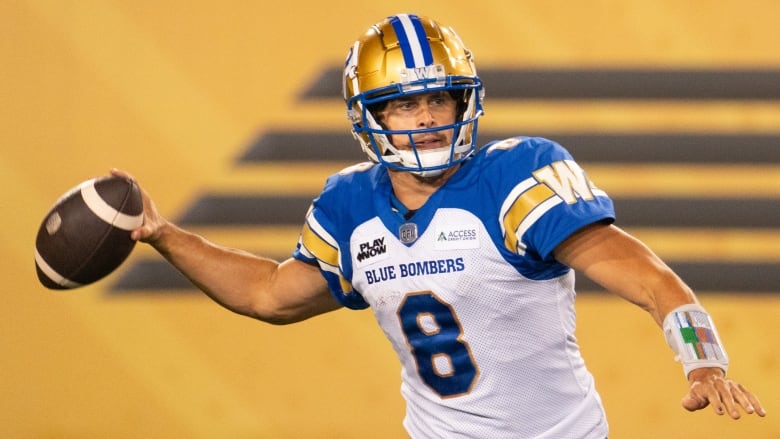 A football quarterback hold a ball in one hand, preparing to throw