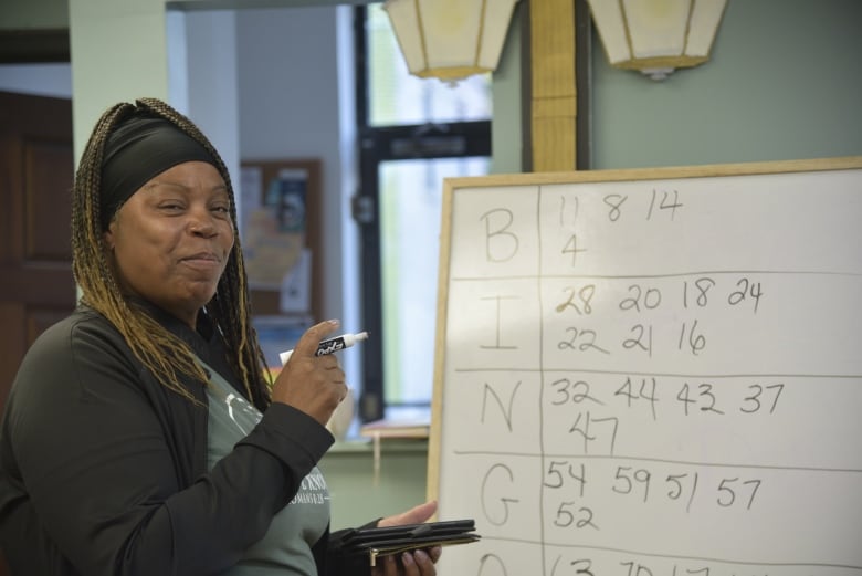 A woman smiles with a bingo board in the background