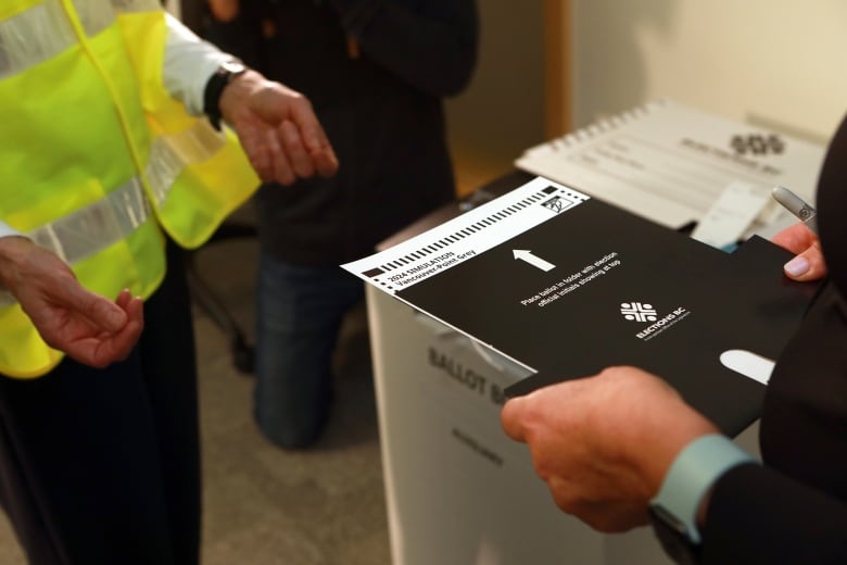 A person holds out a voting card to a poll worker.