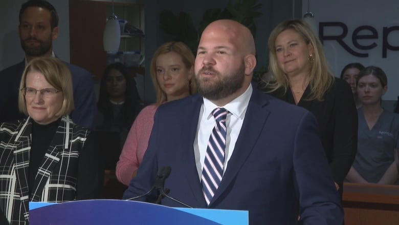 Man in a suit speaking at a news conference