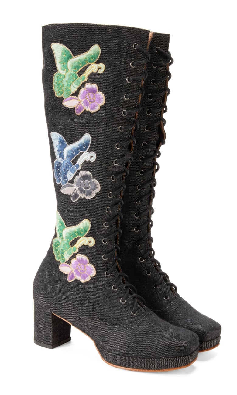 A tall pair of black boots with flowered embroidery.