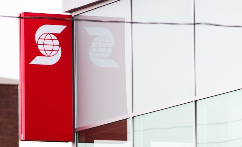 A red sign on a building shows a stylized white logo with an 