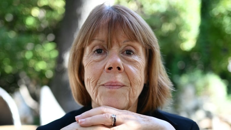 An  older, poised woman looks intently at the camera