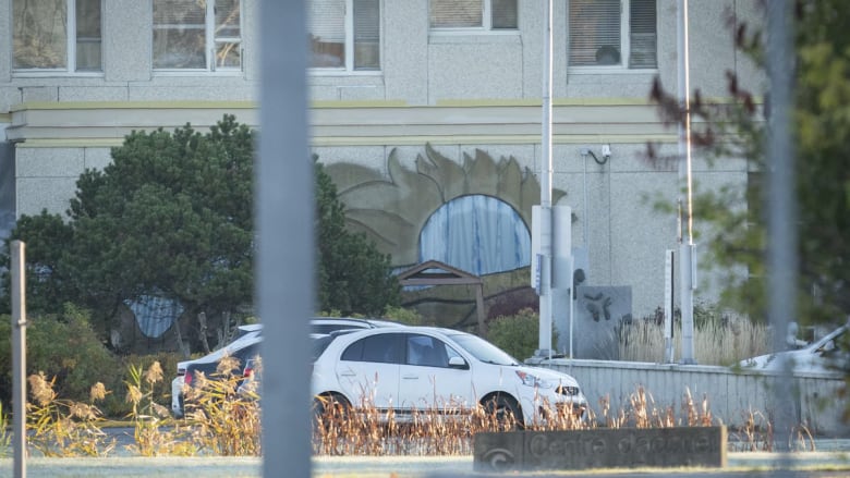 Two cars pass in front of a building.