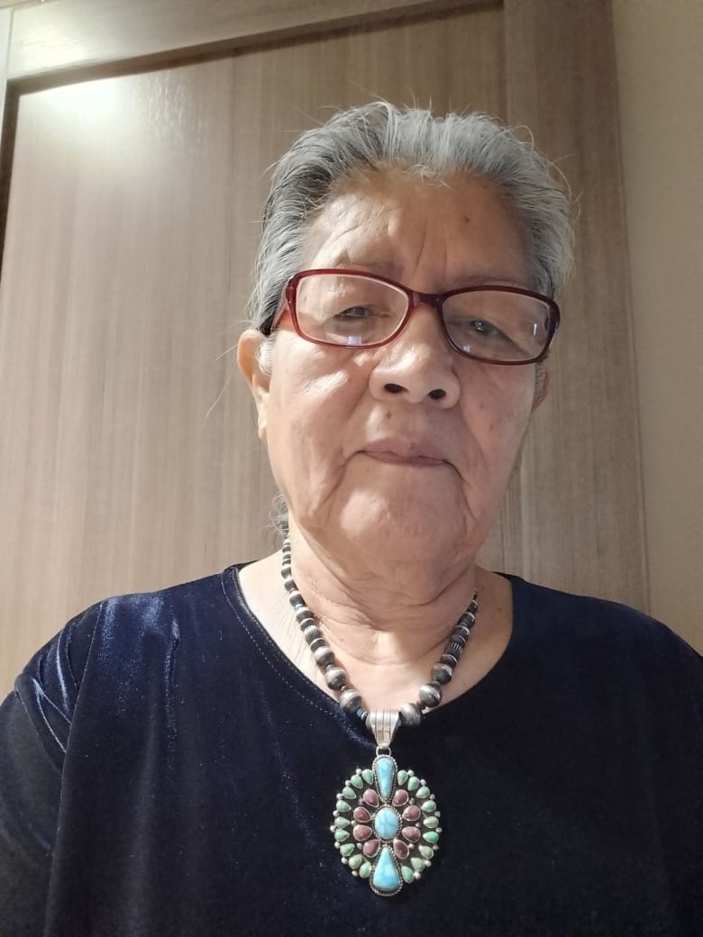 A headshot of a woman in a turquoise beaded necklace.