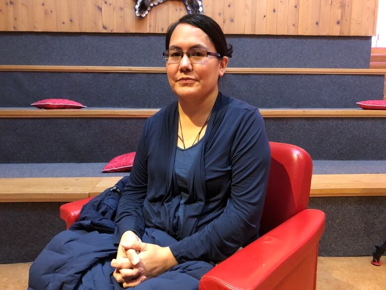 A woman sits in a red chair.