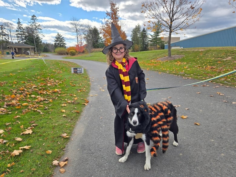 A girl dressed as Harry Potter next to a dog wearing a spider costume.