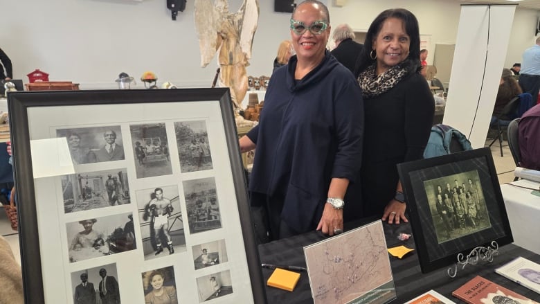 Two women next to a large frame holding several old photographs.