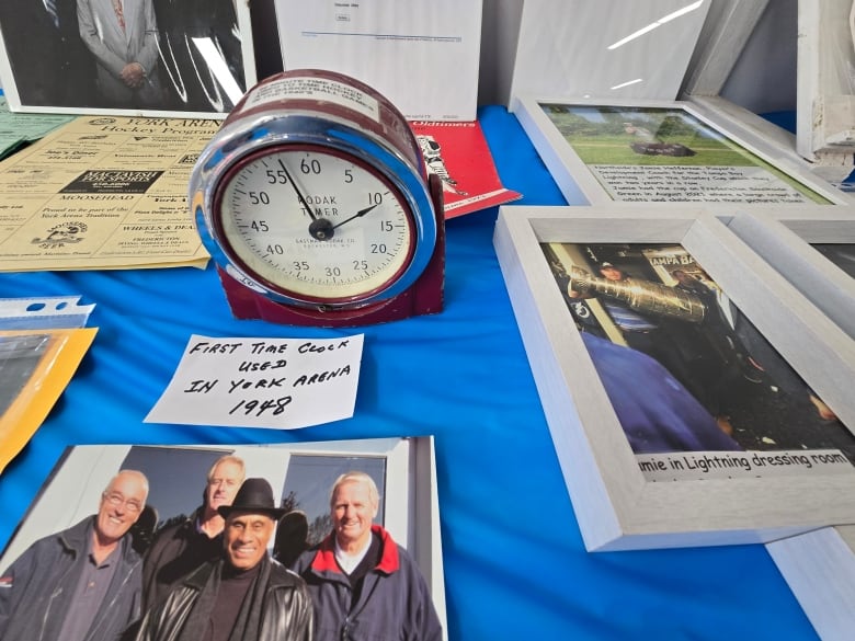 A red clock on a table full of other items.