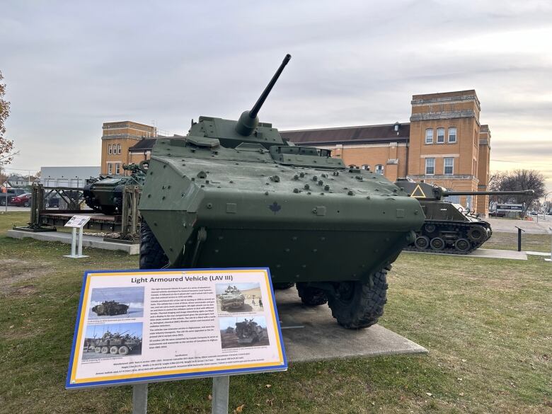 An armored vehicle on top of a concrete platform outdoors, with a plaque in front of it that says 'Light Armoured Vehicle (LAV III).'