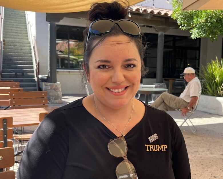 A woman sits outside on a patio. 