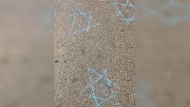 Blue Stars of David drawn with chalk on a sidewalk.