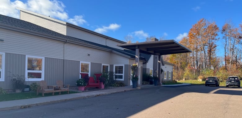 A long, low building with a sloped roof and sturdy lawn chairs in landscaped areas out front.