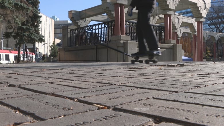 Bricks are pictured along a floor with a skateboarder pictured in the background.