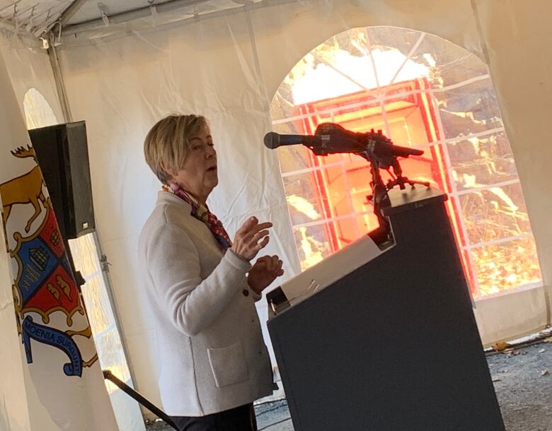 Woman speaking at a microphone at a podium.